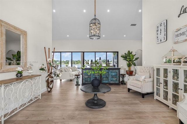 interior space featuring a notable chandelier, a towering ceiling, and light hardwood / wood-style flooring