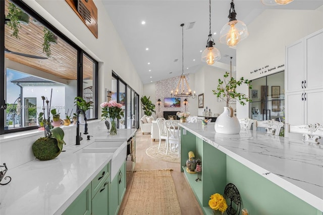 kitchen featuring sink, green cabinetry, light wood-type flooring, hanging light fixtures, and vaulted ceiling