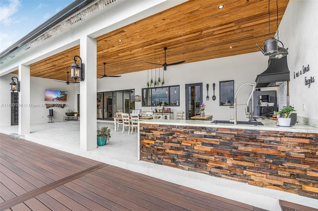 wooden terrace featuring an outdoor bar, a patio area, and ceiling fan