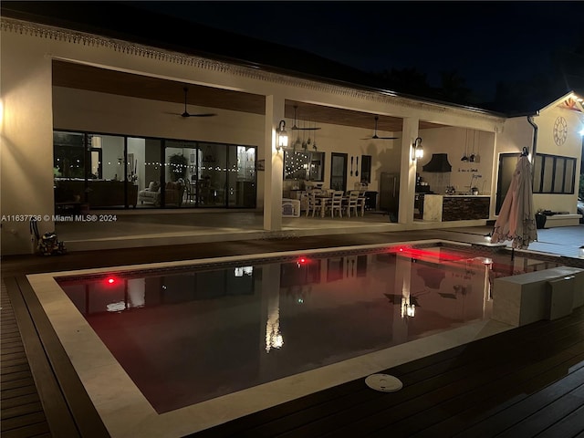 pool at night featuring a patio area and ceiling fan