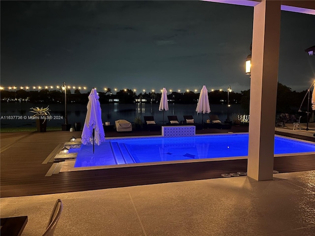 pool at twilight featuring a patio area and a water view