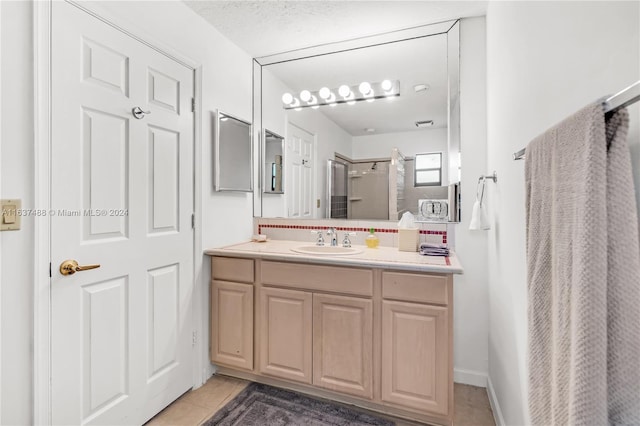 bathroom with a textured ceiling, vanity, tile patterned floors, and walk in shower