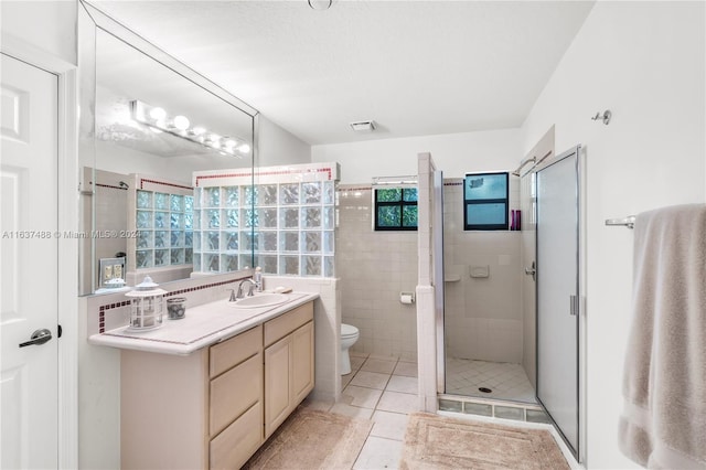 bathroom with tile patterned flooring, vanity, a shower with shower door, and toilet