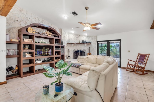 living room with ceiling fan, a fireplace, light tile patterned flooring, and french doors