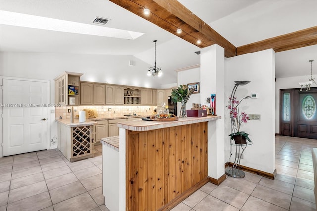 kitchen featuring kitchen peninsula, pendant lighting, light tile patterned floors, and beamed ceiling