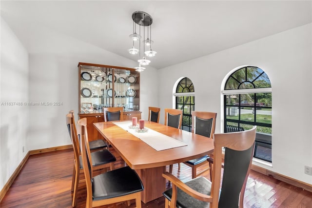 dining area with wood-type flooring and vaulted ceiling