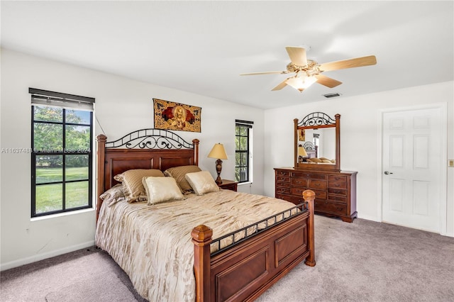 bedroom featuring multiple windows, ceiling fan, and light colored carpet