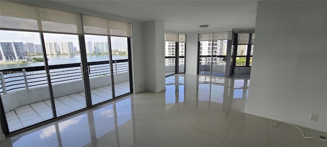 empty room with a wall of windows, tile patterned floors, and a water view