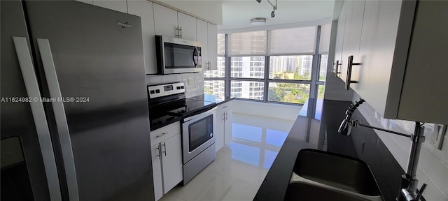 kitchen with white cabinets, decorative backsplash, appliances with stainless steel finishes, and light tile patterned floors