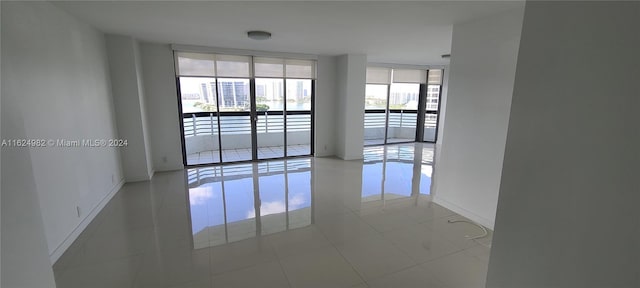 spare room with a wall of windows and tile patterned floors