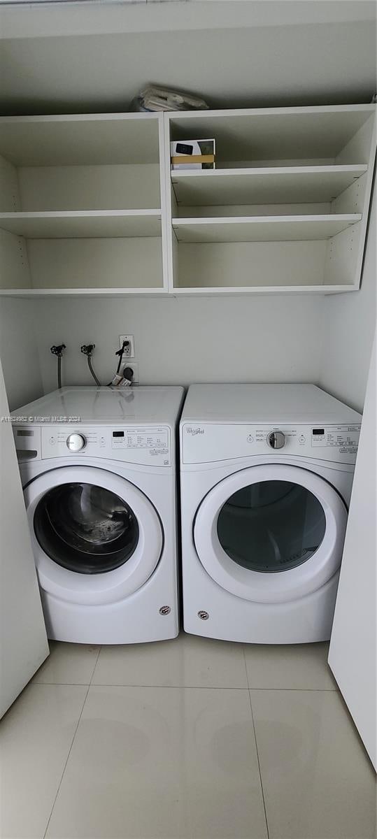 clothes washing area featuring light tile patterned flooring and washing machine and clothes dryer