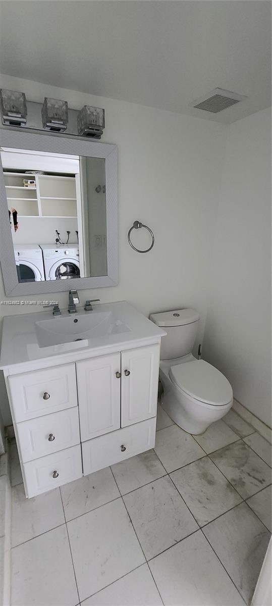 bathroom with vanity, toilet, washer and clothes dryer, and tile patterned flooring