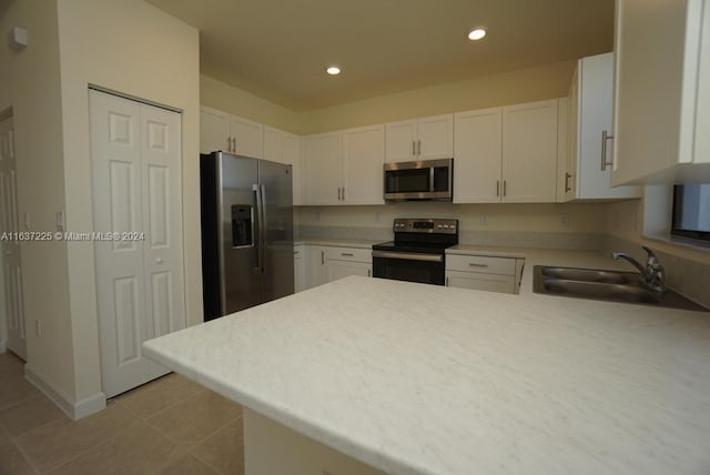 kitchen with appliances with stainless steel finishes, white cabinetry, kitchen peninsula, and sink