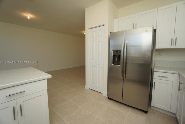 kitchen featuring light tile patterned floors, baseboards, light countertops, white cabinets, and stainless steel fridge