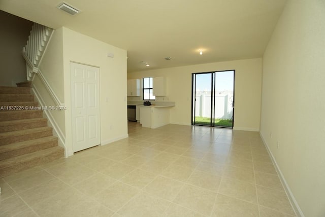 unfurnished room featuring light tile patterned floors, visible vents, baseboards, and stairs