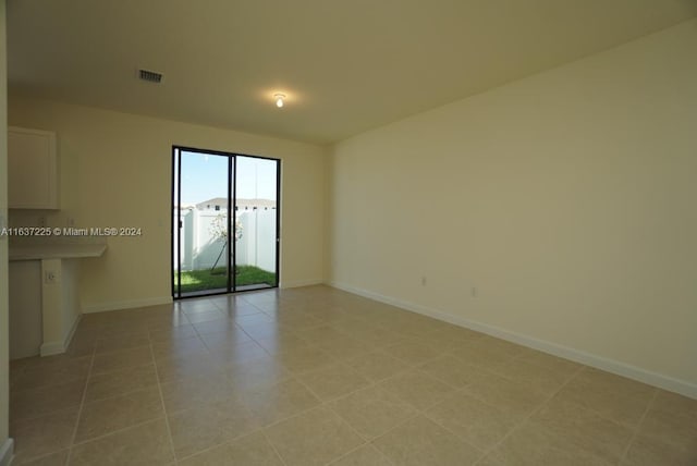 spare room featuring light tile patterned floors, visible vents, and baseboards