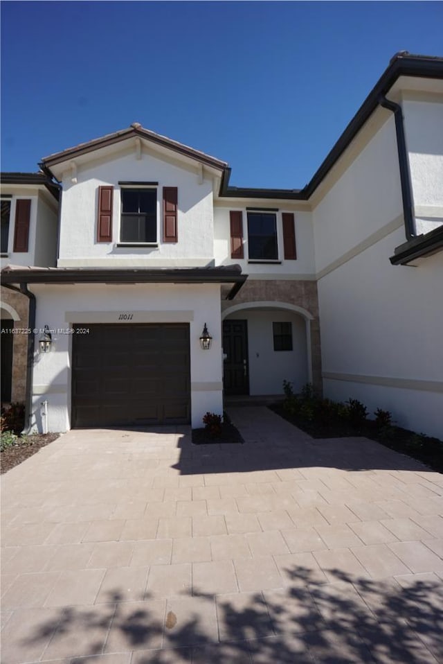 view of front of property featuring decorative driveway, a garage, and stucco siding