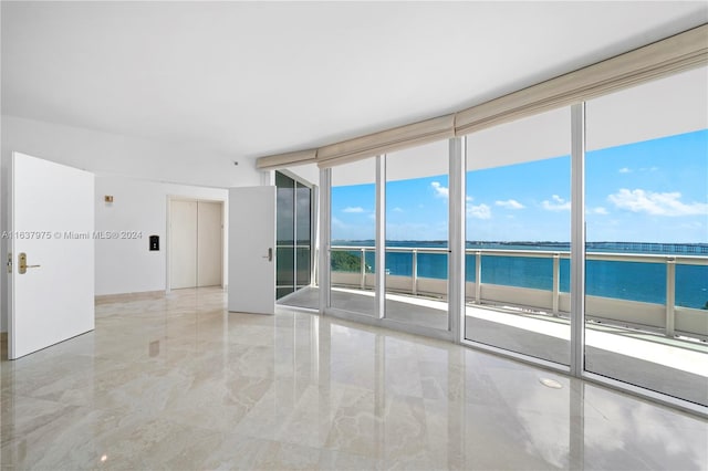 spare room featuring a wall of windows, plenty of natural light, and a water view