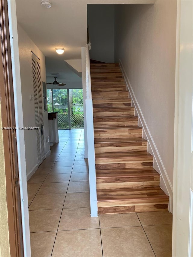 stairway featuring tile patterned flooring and ceiling fan