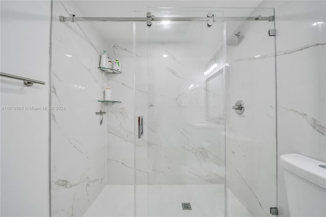 bathroom featuring a shower with shower door and toilet