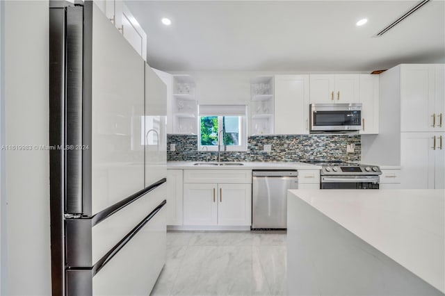 kitchen with decorative backsplash, white cabinetry, appliances with stainless steel finishes, light tile patterned floors, and sink