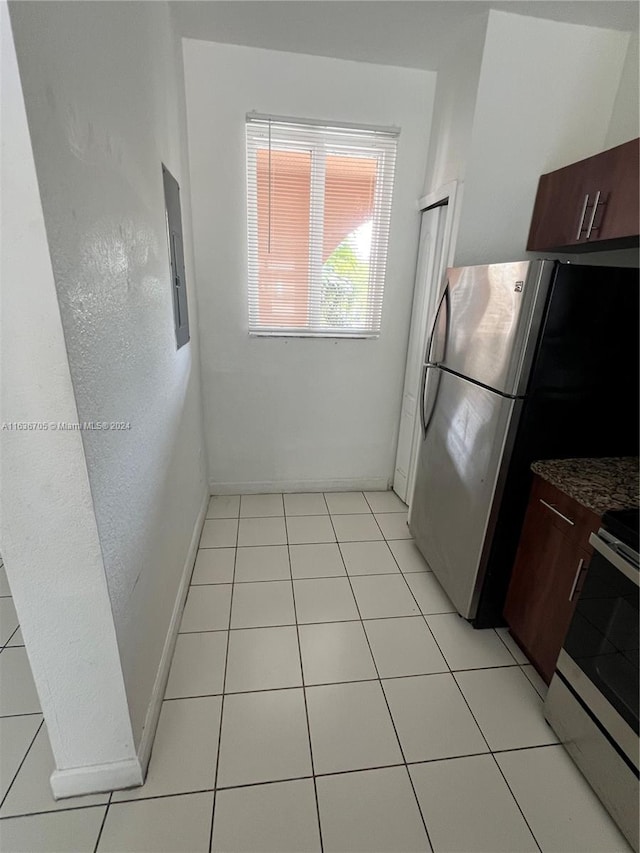 kitchen featuring light tile patterned floors, stainless steel appliances, dark brown cabinetry, and electric panel