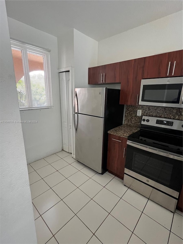 kitchen with stainless steel appliances, light tile patterned floors, and backsplash