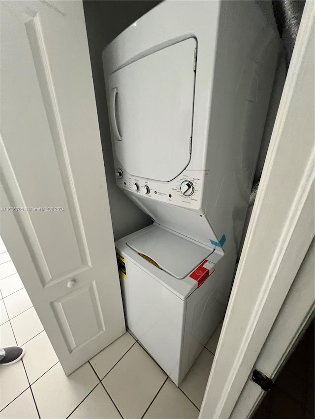 laundry area with stacked washer / dryer and light tile patterned flooring