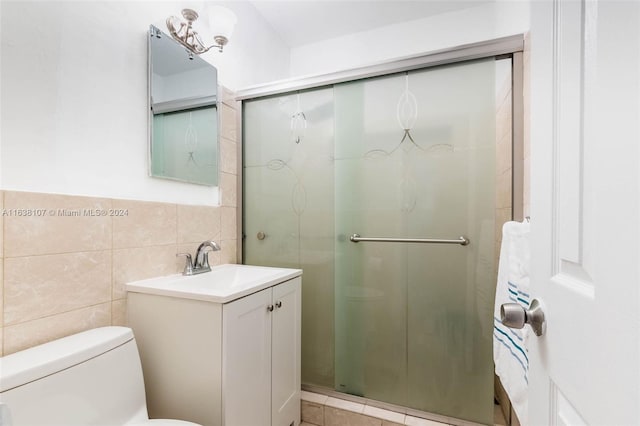 bathroom featuring walk in shower, vanity, tile walls, and toilet