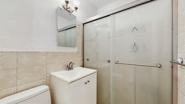 bathroom featuring vanity, toilet, an enclosed shower, and tile walls