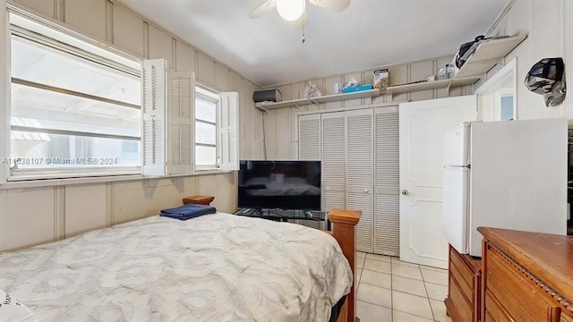 tiled bedroom featuring ceiling fan, a closet, and white fridge