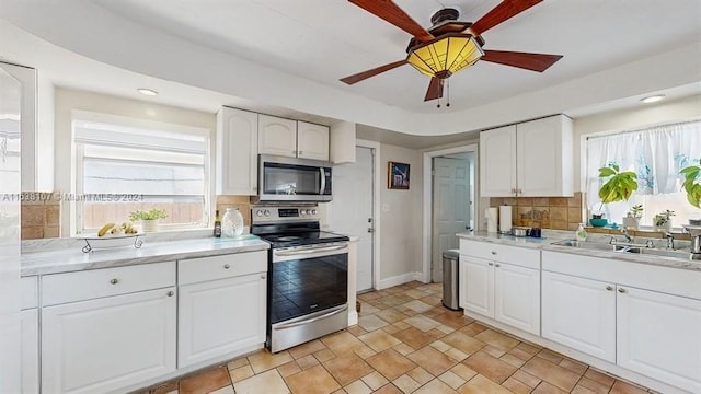 kitchen with white cabinets, appliances with stainless steel finishes, ceiling fan, and sink