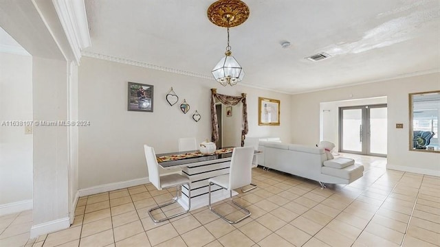 tiled dining room featuring crown molding and french doors