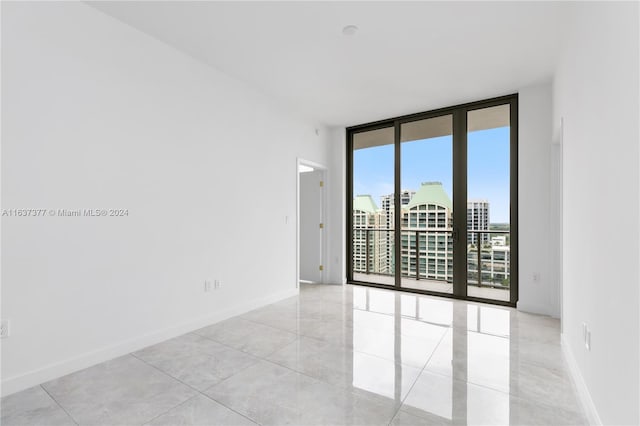 unfurnished room featuring a wall of windows and light tile patterned floors