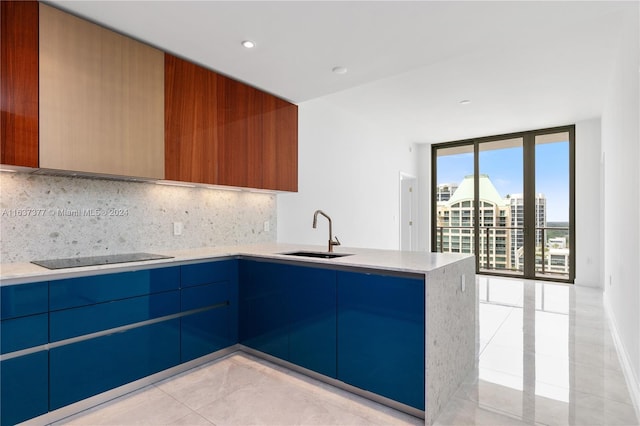 kitchen with light tile patterned flooring, decorative backsplash, sink, light stone countertops, and kitchen peninsula