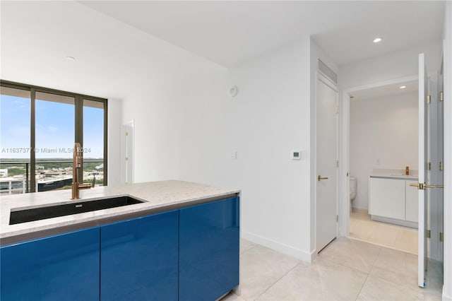 kitchen with sink, light stone countertops, and light tile patterned floors