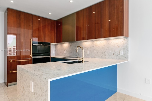 kitchen with sink, black double oven, kitchen peninsula, light tile patterned floors, and decorative backsplash