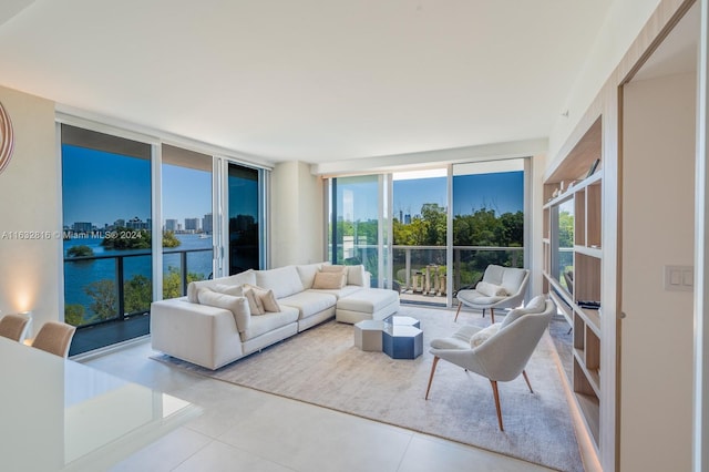 living room featuring light tile patterned floors, a water view, and expansive windows