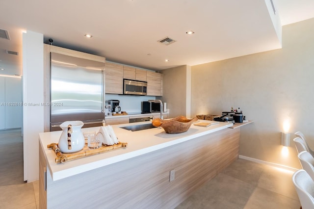 kitchen with appliances with stainless steel finishes, light brown cabinetry, and light tile patterned floors