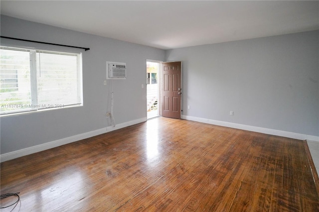 unfurnished room with wood-type flooring and a wall mounted air conditioner