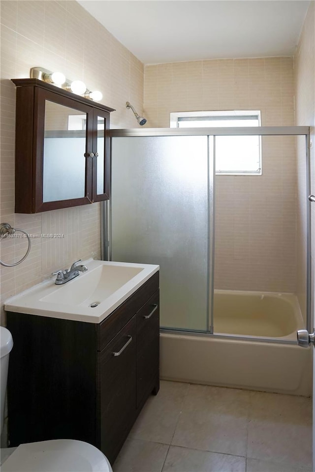 full bathroom featuring vanity, tile walls, enclosed tub / shower combo, and toilet