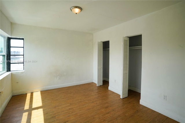 unfurnished bedroom featuring multiple closets and hardwood / wood-style flooring