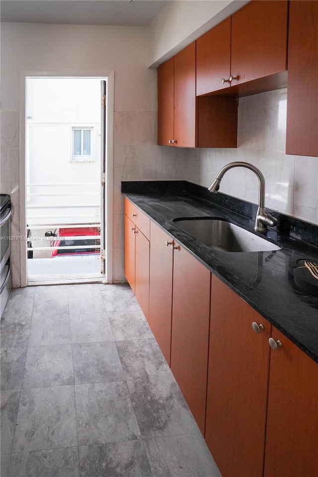 kitchen featuring dark stone countertops, decorative backsplash, sink, and light tile patterned floors