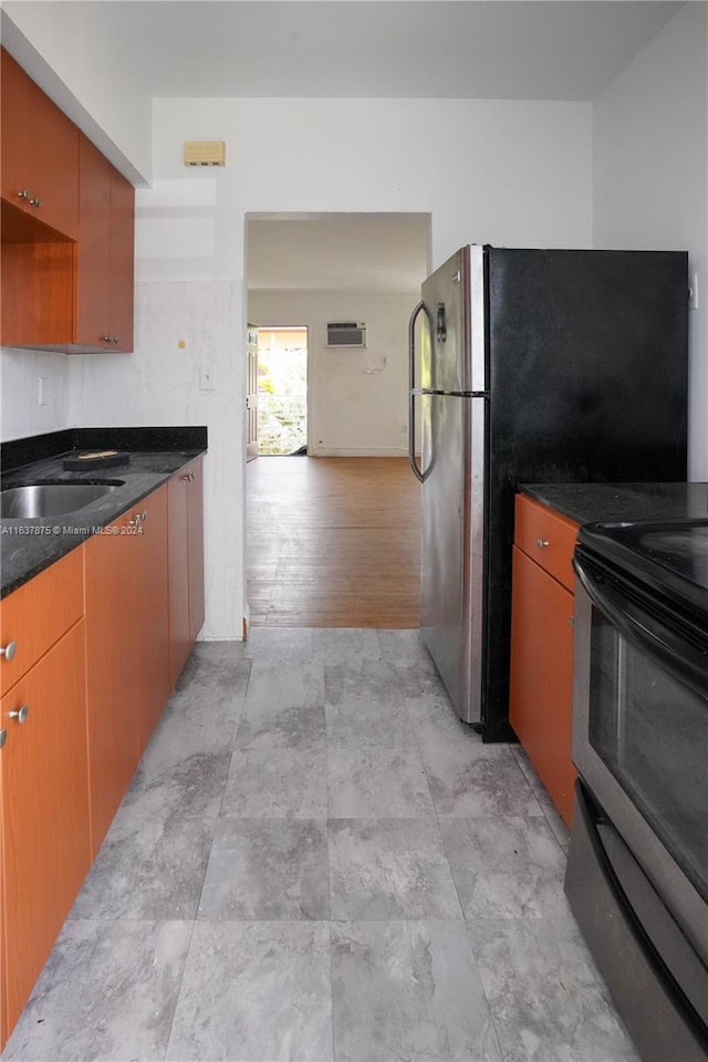 kitchen with dark stone counters, stainless steel appliances, light hardwood / wood-style flooring, and sink