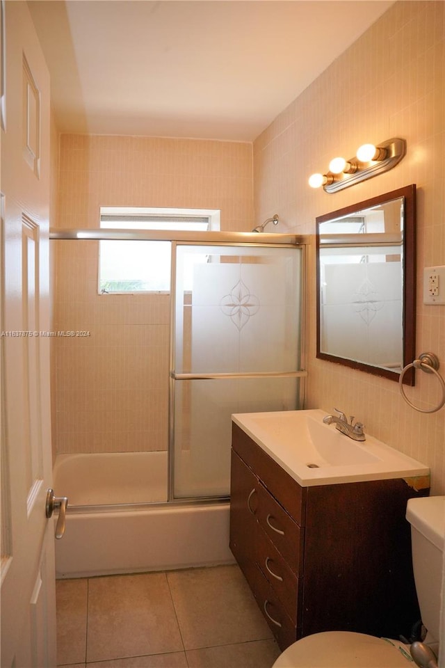 full bathroom featuring vanity, tile walls, enclosed tub / shower combo, and toilet