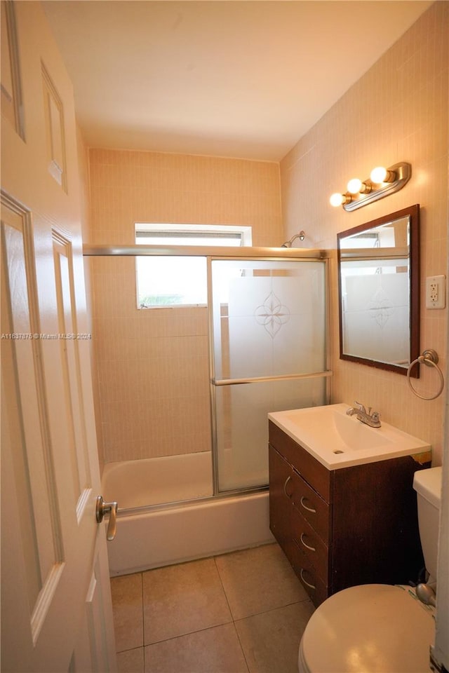 full bathroom featuring enclosed tub / shower combo, tile walls, tile patterned floors, toilet, and vanity