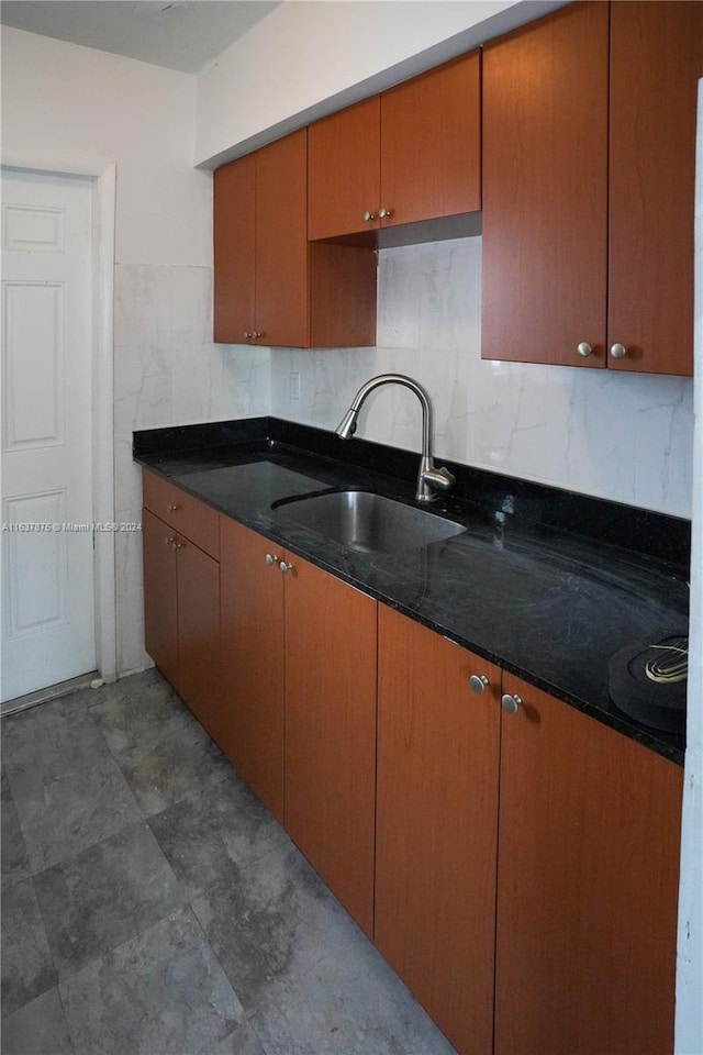 kitchen featuring sink, decorative backsplash, dark stone counters, and dark tile patterned floors