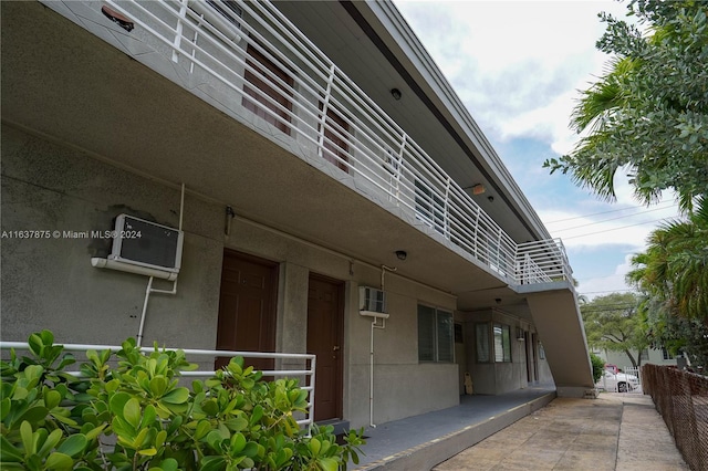 view of property exterior featuring a wall mounted AC and a balcony