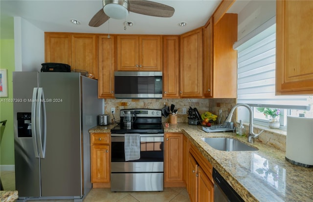 kitchen featuring ceiling fan, stainless steel appliances, decorative backsplash, sink, and light stone counters