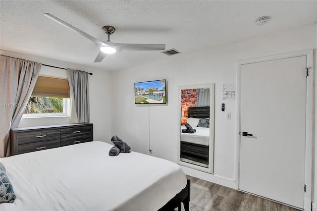 bedroom featuring light hardwood / wood-style floors, a textured ceiling, and ceiling fan